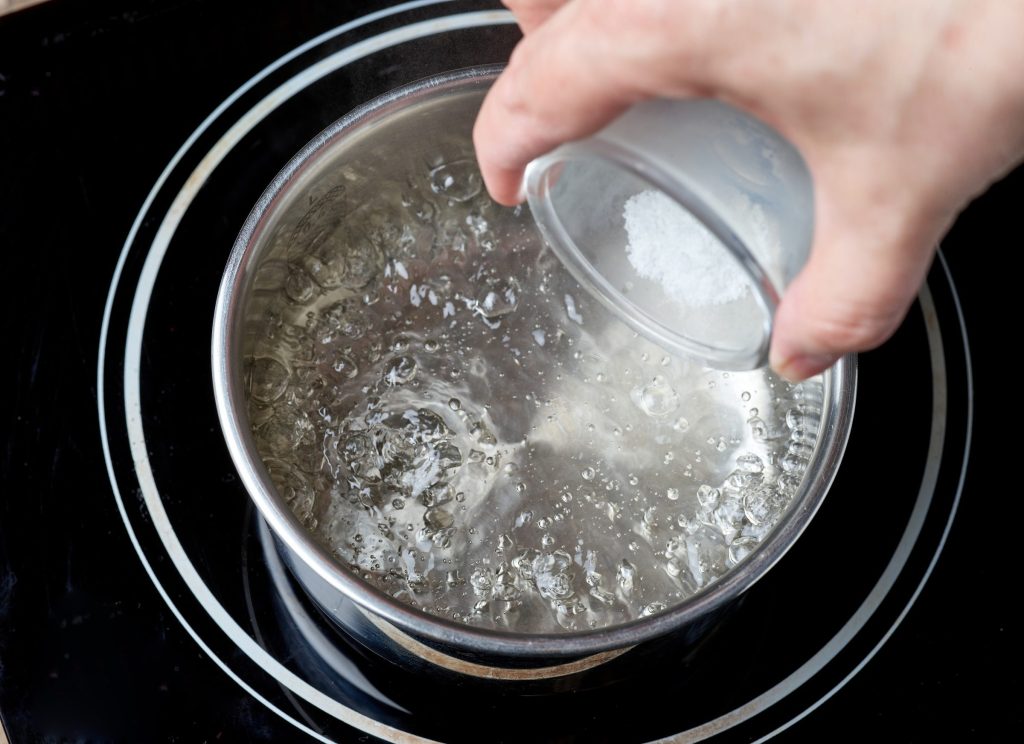 A measure of descaling powder going into simmering water.