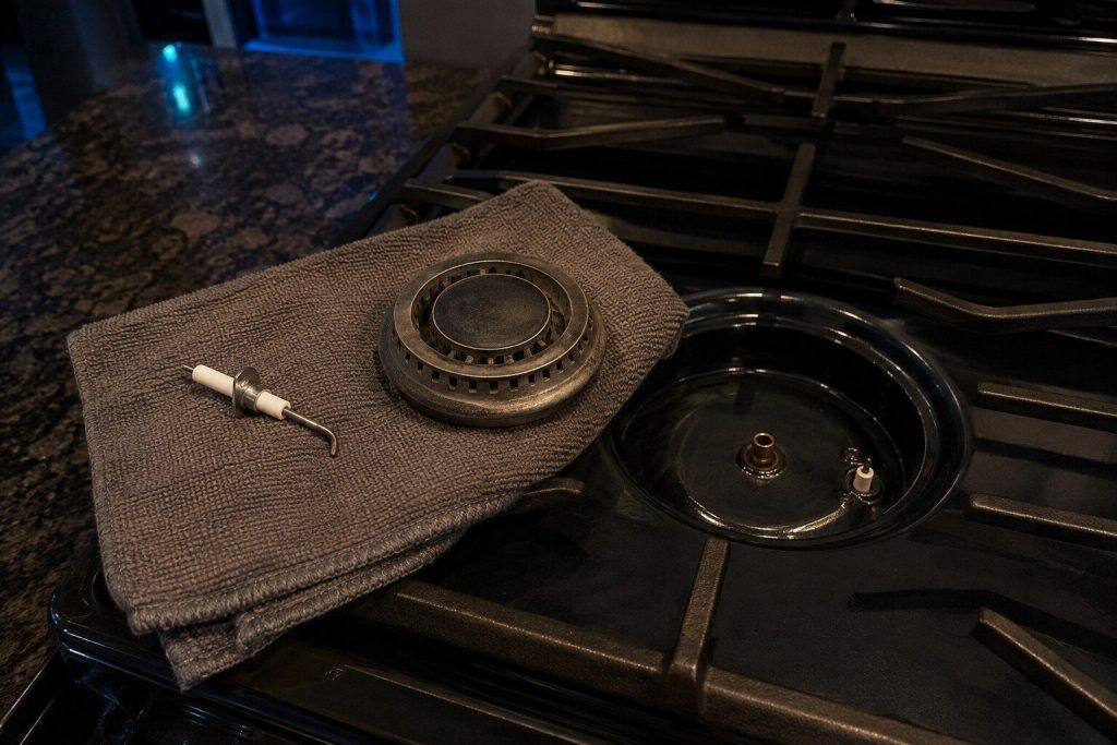 A spark igniter and a burner head lying apart on a folded towel beside the empty burner base